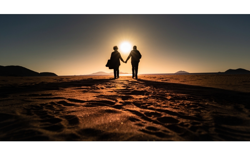 深秋的早上，嵊泗海边，两位老人手牵手在沙滩上散步...........